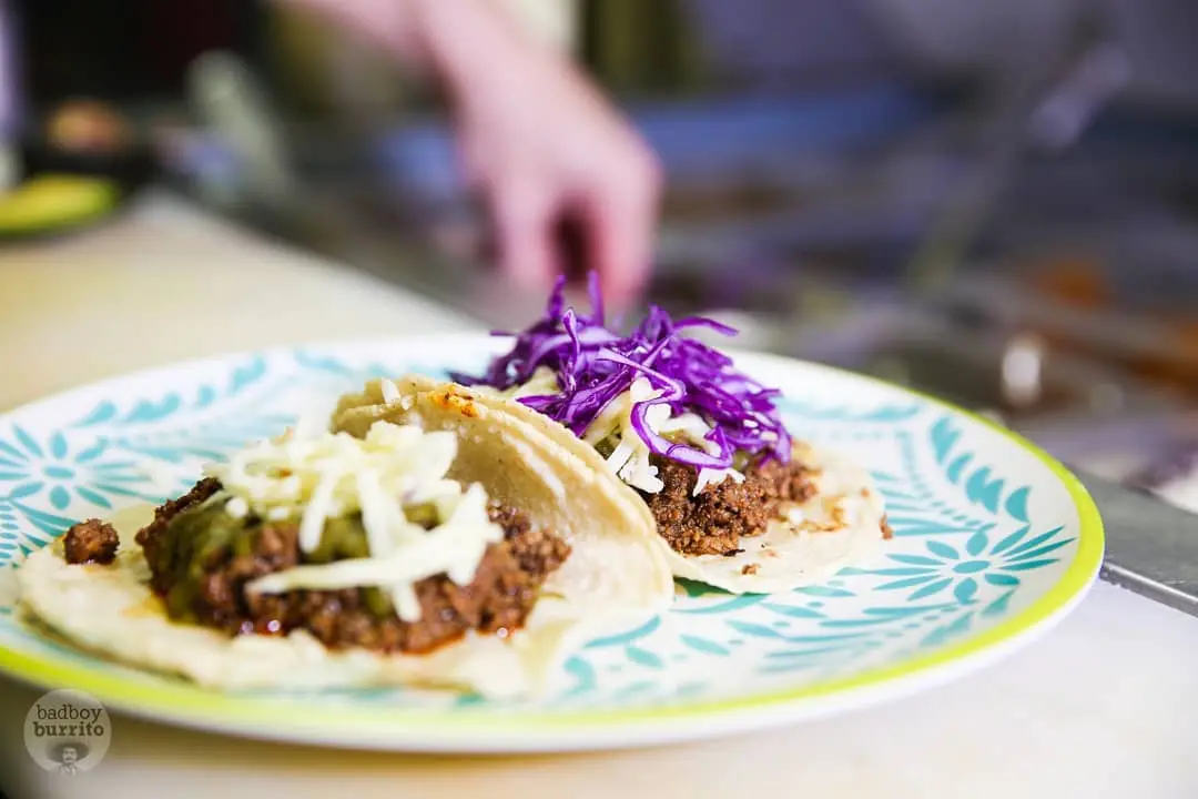 Beef tacos topped with cheese and purple cabbage